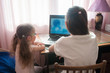 © Kiryakova Anna - Two girls, the oldest and the youngest, are engaged at a table on a laptop. Little sister with glasses.