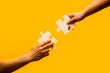 Closeup Hands Of Man Connecting Jigsaw Puzzle. Business Solutions, Success And Strategy Concept. Two Hands Trying To Connect Couple Puzzle With Yellow Background