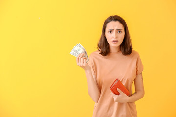 Poster - Sad young woman with wallet and money on color background