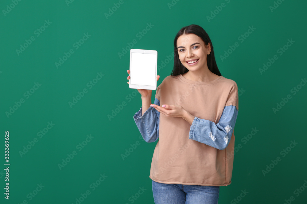 Beautiful young woman with tablet computer on color background