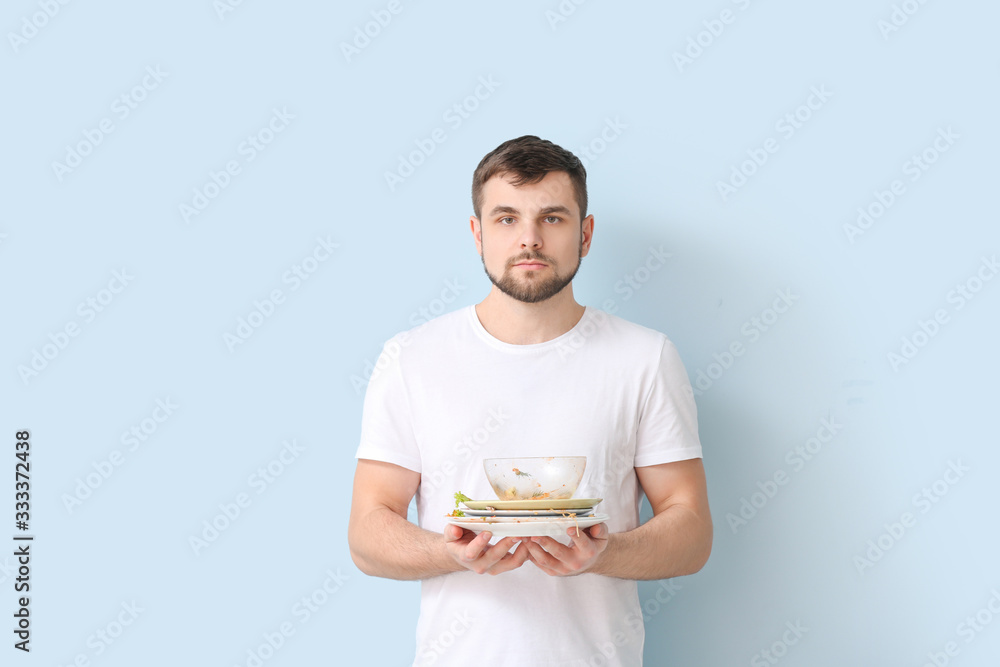 Man with dirty dishes on color background