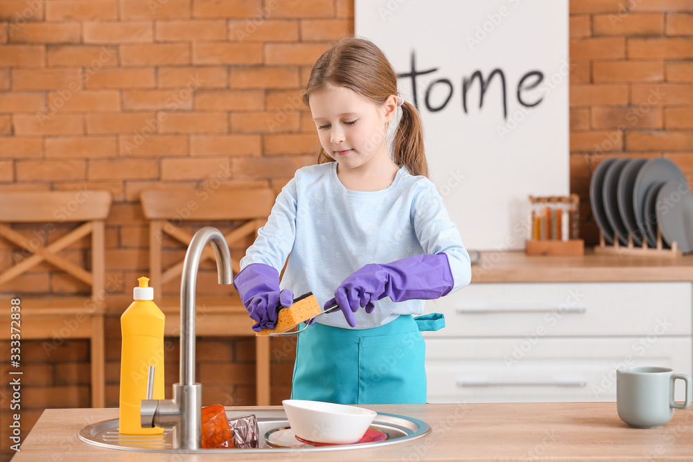 Little girl washing dirty dishes in kitchen