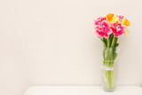 Fototapeta Tulipany - Beautiful spring tulips in vase on table against light background with a copy space