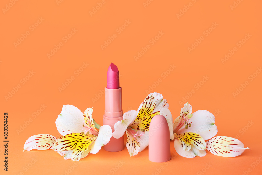 Lipstick and flowers on color background
