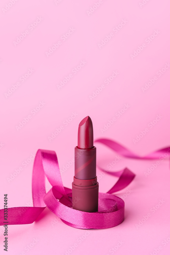 Lipstick and ribbon on color background