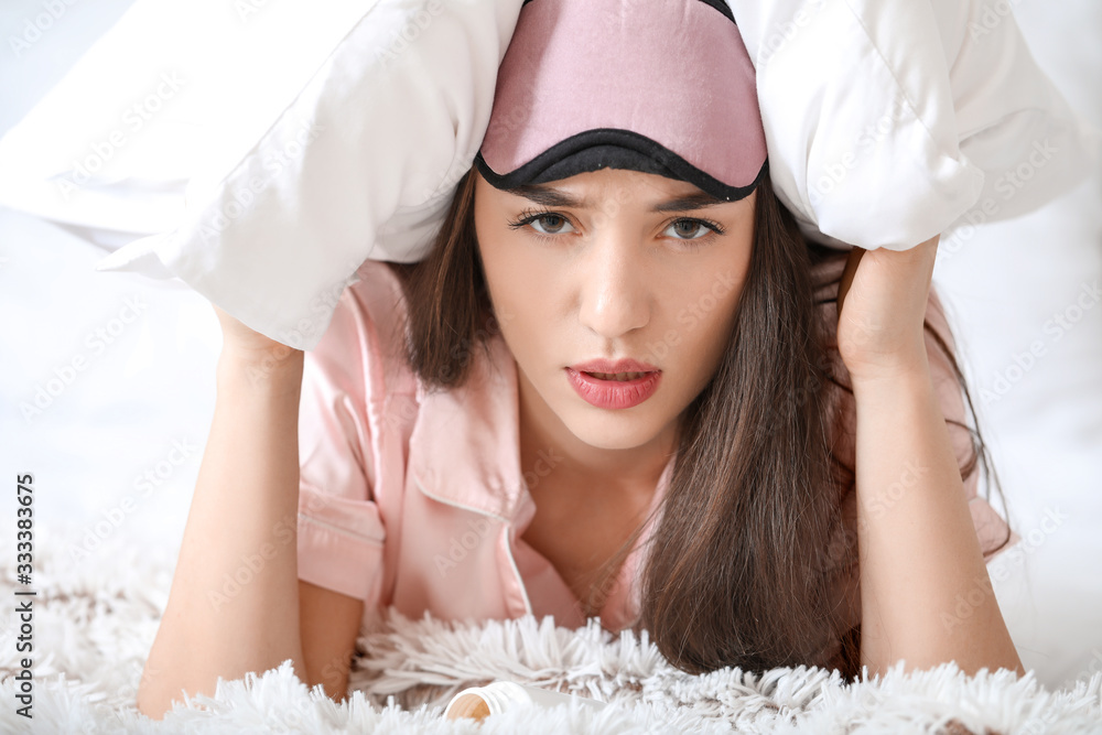 Tired woman with pillow in bedroom