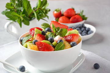 Bowl of healthy fresh colorful fruit salad on wooden background. Top view.Fruit salad with strawberry, blueberry, sweet cherry, kiwi.Vegetarian food concept. Rustic wooden background