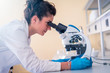 © Vladimir Borovic - Young female scientist looking through a microscope in a laboratory doing research on finding medicine pharmacy cure vaccine