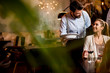© BGStock72 - Smiling young female friends at a restaurant with waiter serving dinner