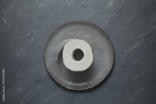 Cuadros en Lienzo Gray plate with a roll of toilet paper on a gray background