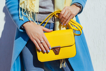 Fashion. Young woman holding stylish handbag and wearing trendy blue coat. Spring female clothes and accessories.