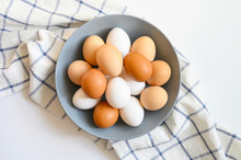 Chicken Eggs White And Brown Color In A Gray Plate On A Checked Kitchen Towel On A White Table. Concept Farm Products And Natural Nutrition