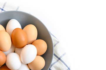 chicken eggs white and brown color in a gray plate on a checked kitchen towel on a white table. concept farm products and natural nutrition. space for text