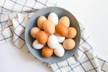 chicken eggs white and brown color in a gray plate on a checked kitchen towel on a white table. concept farm products and natural nutrition