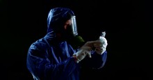 A Man In A Protective Gas Mask. A Person Clicks On The Touch Screen Of A Phone Wearing A Chemical Suit