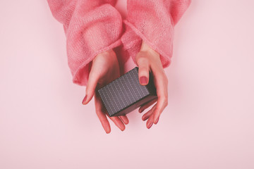 Woman hands with pink manicure hold black gift box