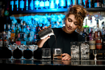 Wall Mural - barman lady pours the finished cocktail into glass.