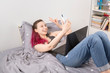 © matucha12 - Concept - work from home, self-isolation. Young girl lies in bed, takes selfies, moral support