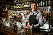 © fesenko - Young handsome bartender holds in his hands steel shaker and empty glass