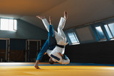 Two young judo caucasian fighters in white and blue kimono with black belts training martial arts in the gym with expression, in action, motion. Practicing fighting skills. Overcoming, reaching target