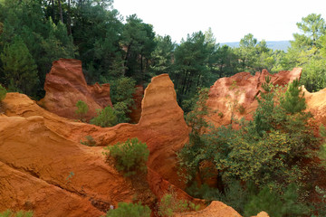 Ochre Trail in Roussillon, Sentier des Ocres, hiking path in a natural colorful area of red and yellow cliffs in a disused ocher pigment quarry surrounded by green forest in Provence, Southern France