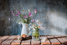 Beautiful Bouquets Of Wildflowers On A Wooden Table On A Cold Concrete Wall Background.
