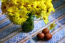 Yellow Wildflowers In A Vase And 3 Eggs For Easter On The Table