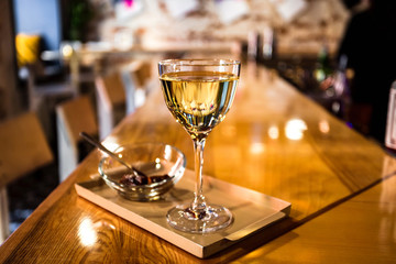 Wall Mural - A photo of a light yellow transparent cocktail in a nick and nora glass, served on a small tray with garnish in a small glass bowl