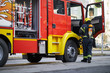 © luckybusiness - Fireman in uniform in front of fire truck going to rescue and protect. Emergancy servise concept.