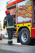 © luckybusiness - Fireman in uniform in front of fire truck going to rescue and protect. Emergancy servise concept.