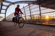Caucasian Woman Riding a Bicycle on a Pedestrian Bridge over the Highway during a sunny sunset. Taken in Surrey, Vancouver, British Columbia, Canada.