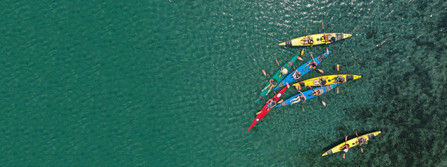 Aerial drone ultra wide photo of young athlete team practising sport canoe in tropical exotic bay with emerald sea