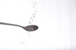 coarse salt falling on spoon on white background