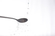 liquid falling on a metallic spoon on white background