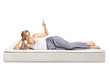 © Ljupco Smokovski - Young woman lying on a comfortbale mattress in pajamas and pointing up