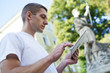 © shyshka - young handsome man standing in the street looking for something on his tablet