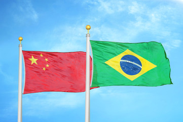 China and Brazil two flags on flagpoles and blue cloudy sky