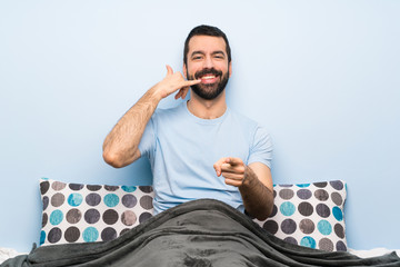 Wall Mural - Man in bed making phone gesture and pointing front