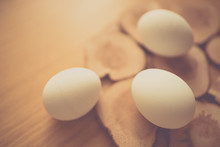 Three White Chicken Eggs On A Wooden Board And Table.