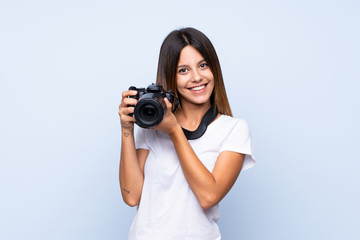 Young woman over isolated blue background with a professional camera