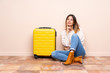 © luismolinero - Traveler woman with suitcase sitting on the floor thinking an idea