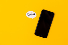 Creative Concept Of Coronavirus. A Black Telephone Lies On A Yellow Background, Next To It Are Paper Message Clouds On Which The Inscriptions Associated With The Covid-19 Virus Are Written