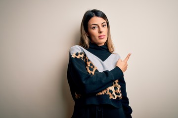 Canvas Print - Young beautiful woman wearing casual sweatshirt standing over isolated white background Pointing with hand finger to the side showing advertisement, serious and calm face