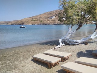 View of sun beds at beautiful Episkopi beach on the charming Greek island of Kythnos.  A horsehoe bay with placed waters, ideal for swimming and cooling off in the summer heat..