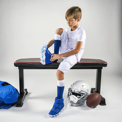 Young football player putting on cleats