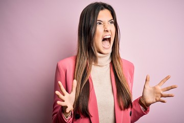 Poster - Young beautiful businesswoman wearing casual turtleneck sweater and jacket crazy and mad shouting and yelling with aggressive expression and arms raised. Frustration concept.