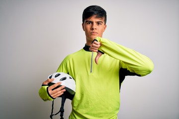 Poster - Young handsome cyclist man holding security bike helmet over isolated white background with angry face, negative sign showing dislike with thumbs down, rejection concept