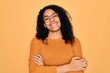 © Krakenimages.com - Young african american woman wearing casual sweater and glasses over yellow background happy face smiling with crossed arms looking at the camera. Positive person.