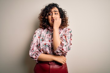 Sticker - Young beautiful curly arab woman wearing floral t-shirt standing over isolated white background looking stressed and nervous with hands on mouth biting nails. Anxiety problem.