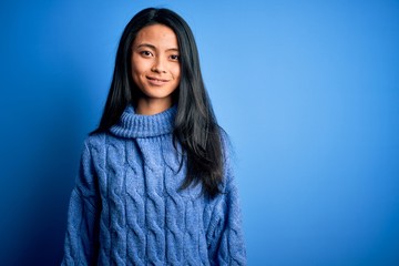 Young beautiful chinese woman wearing casual sweater over isolated blue background with a happy and cool smile on face. Lucky person.